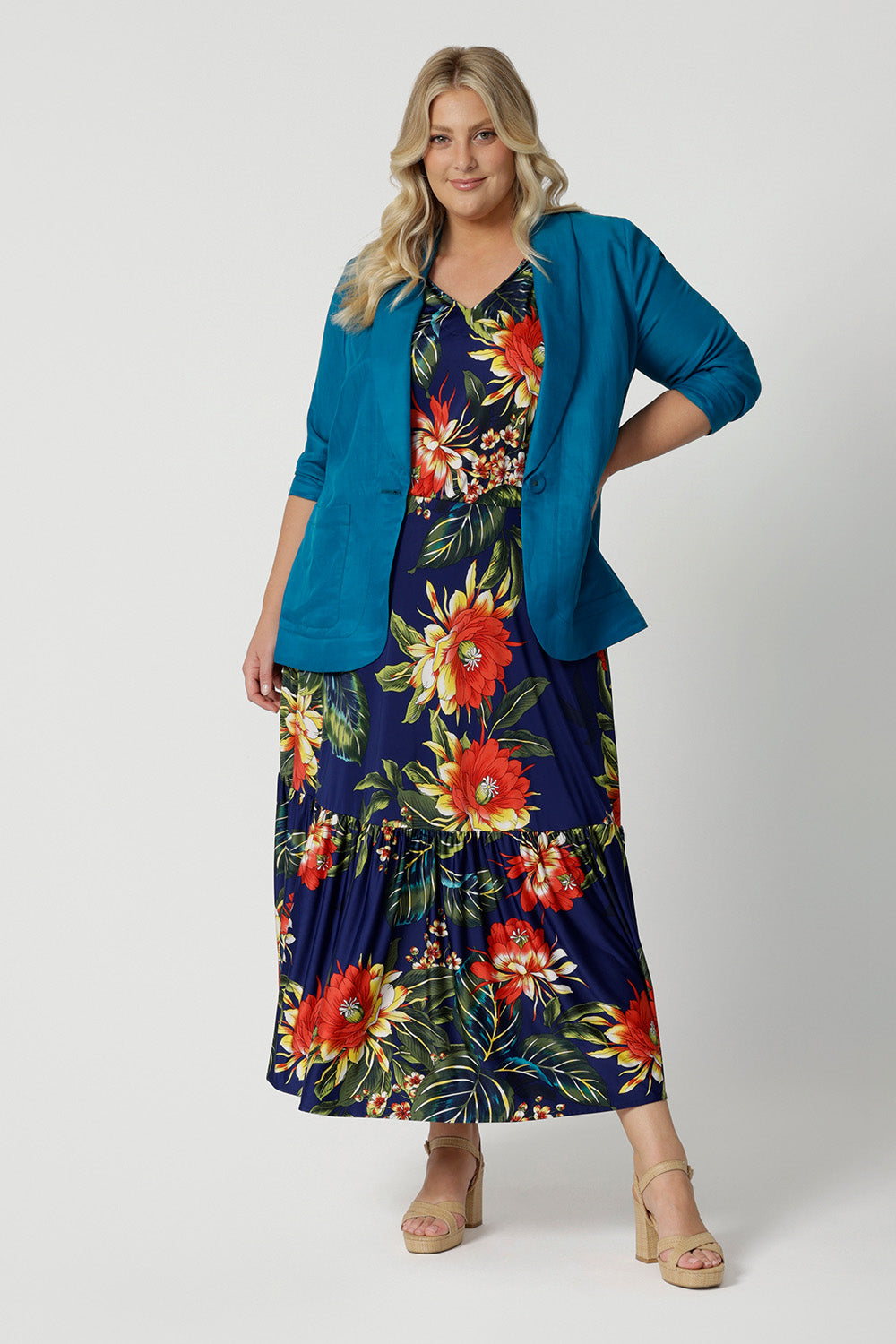 Plus sized woman wears floral maxi dress paired with blazer. This maxi dress is a travel ready piece. Designed in Australia with easy care fabric made of slinky jersey. Leina & Fleur brand stock sizes from 8-24. Shop this summer ready dress in petite sizes and plus sizes.