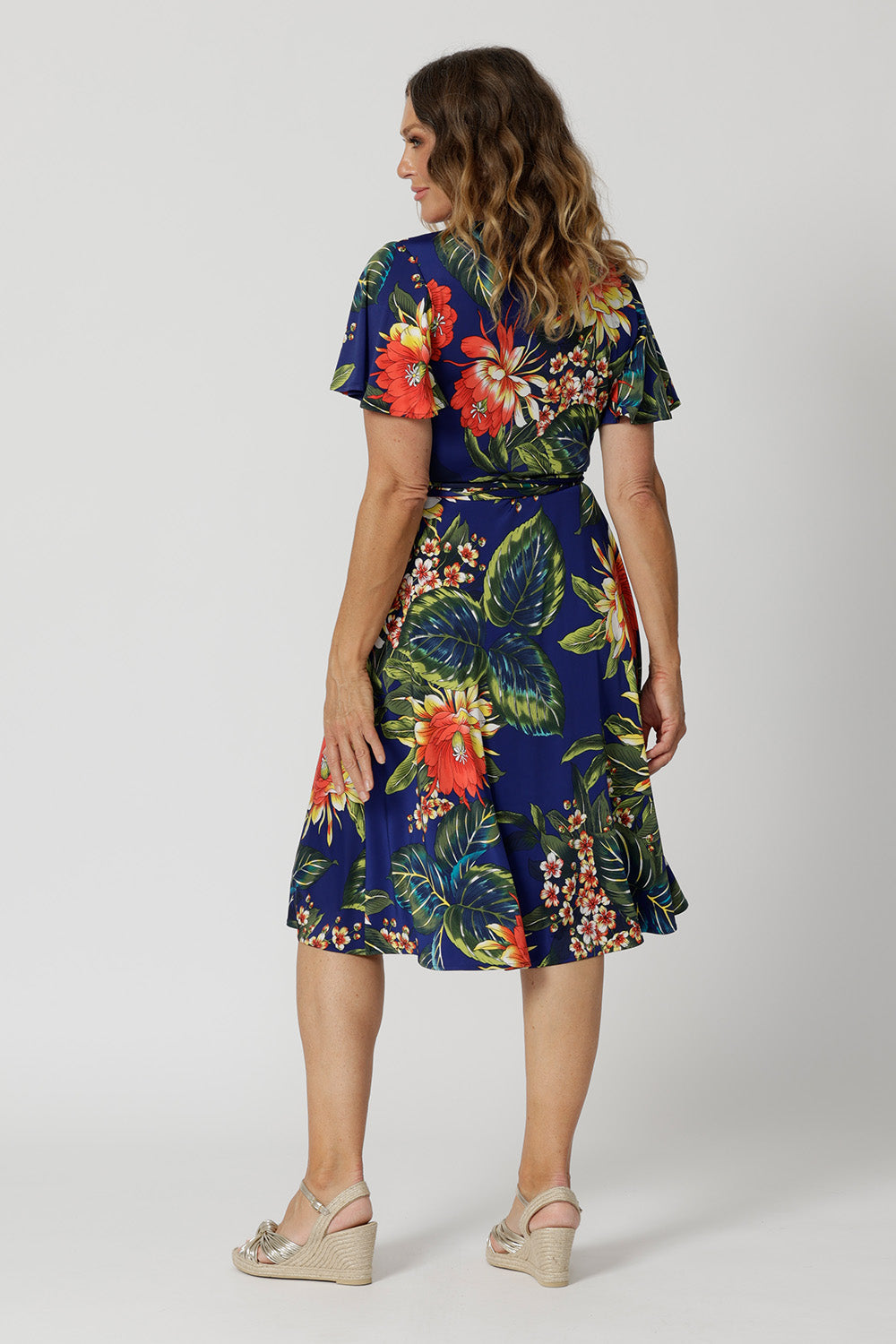 This easy care wrap dress is crease resistant making it perfect for travel. Printed dress has orange, yellow and white flowers on a deep blue base. Designed in Australia with easy care fabric for Australian and New Zealand woman. Sizes 8-24. Proudly made in Australia, supporting local artisans.