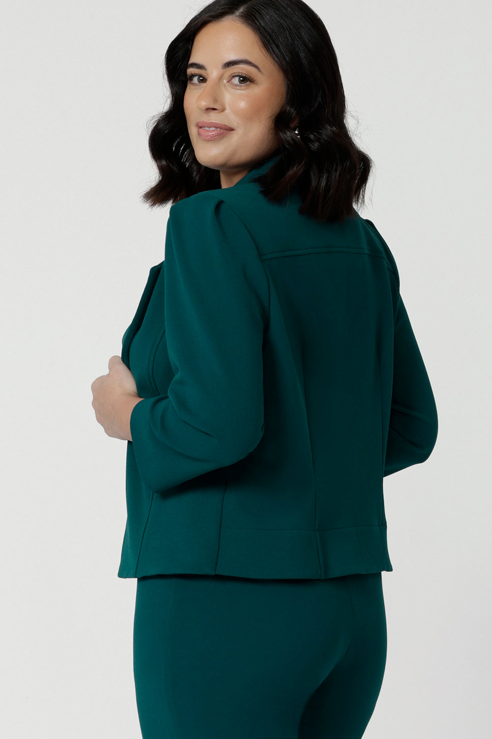 Side view of a great workwear jacket for petite height women. The Benni 3/4 sleeve jacket is worn with tapered leg green workwear pants.
A cropped green jacket , it makes a good workwear suit for women. In sizes 8 to 24, this is a women's jacket for plus size to petite height women by Australian and New Zealand women's clothing brand, Leina & Fleur.