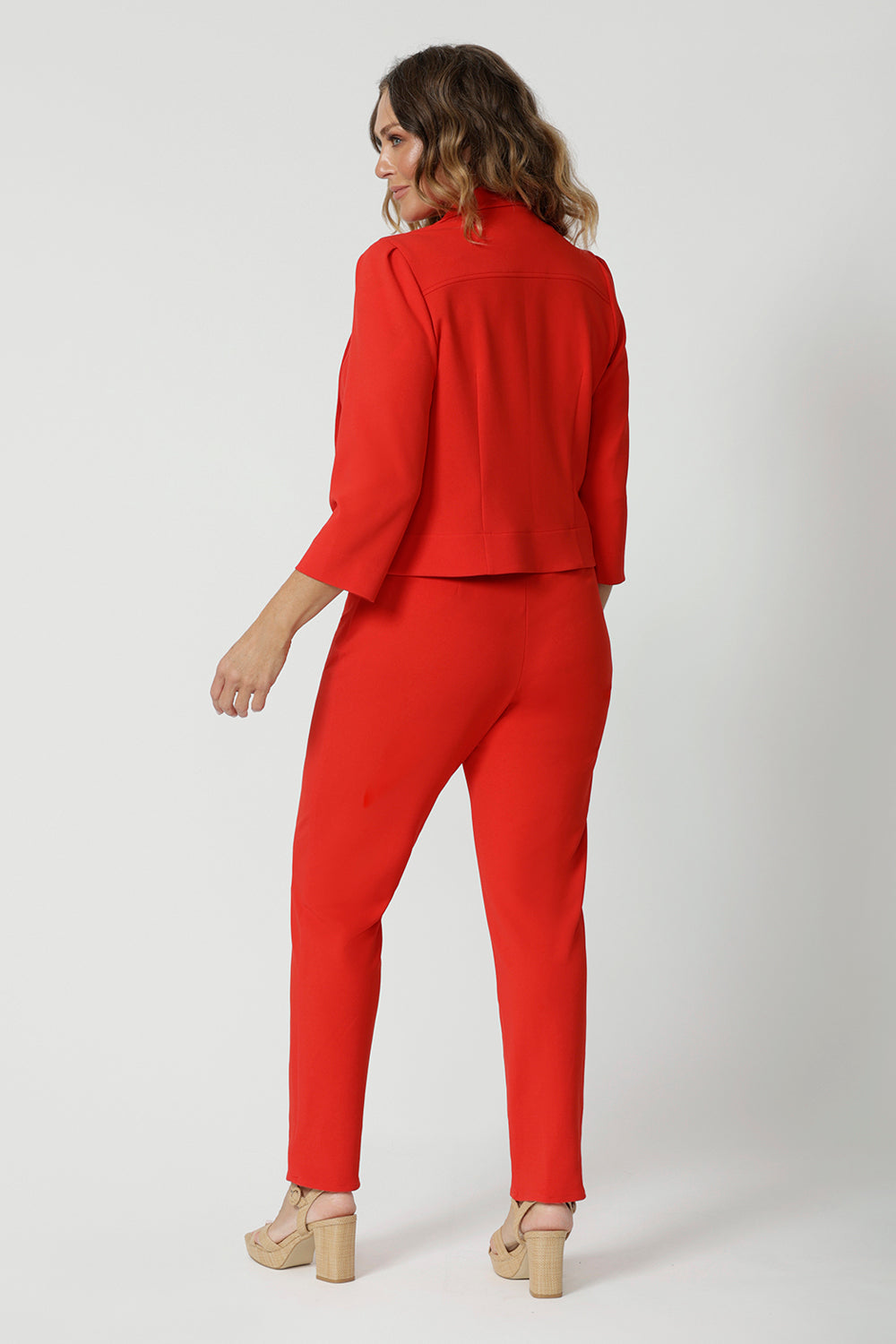The jacket's back features a single layer with tailored darts, enhancing the fit and creating a feminine, contoured silhouette. A shoulder yoke further elevates the design, contributing to its polished, professional feel. The 3/4 length sleeves are subtly detailed with tucks at the sleeve heads, adding a touch of sophistication and texture to the overall look.