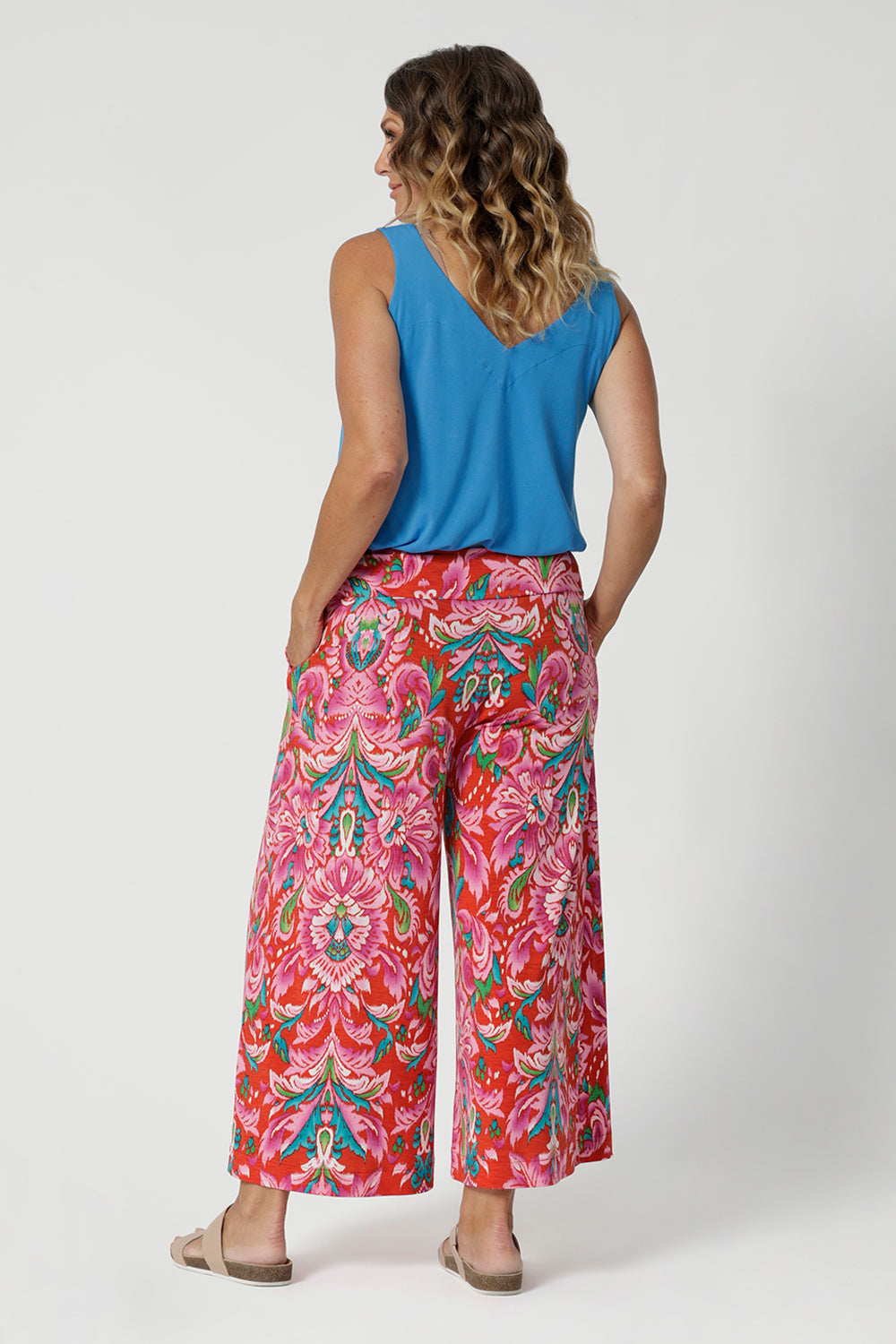 Over 40's woman wears bamboo cami in opal shade, paired back with brightly printed pants, creating a summer ready casual look paired with some flat travel shoes. Cami is stocked in sizes 8-24.