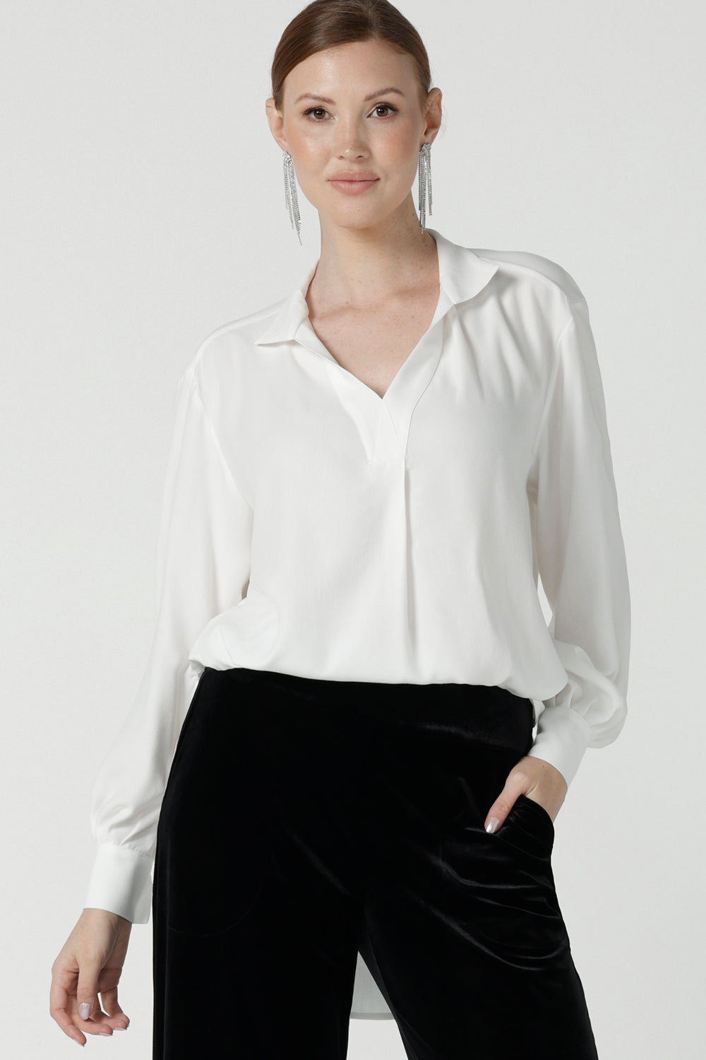 A size 10 woman wears the Ellis shirt in Vanilla tencel, a high quality made in Australia womens shirt made in breathable tencel. Inclusive size range 8-24 and made in Australia. Styled back with the Deni pants in Black velour.