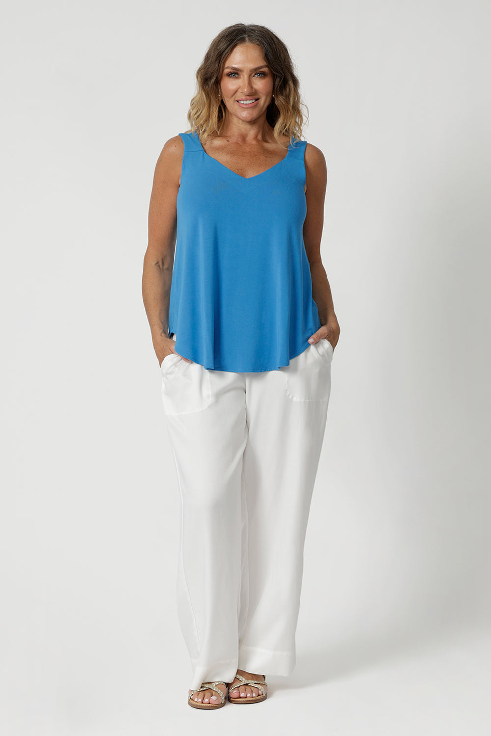 Size 12 woman wears summer cami, that features a shirt-tail hemline providing a relaxed, elongated silhouette, offering a flattering shape that drapes effortlessly over the body. Made from natural bamboo fibres, the fabric boasts exceptional thermoregulating properties, helping to cool the body on warm days and maintain comfort in fluctuating temperatures. This makes the cami perfect for travel, as it adapts to your environment, keeping you fresh and comfortable throughout your journey. Sizes 8-24