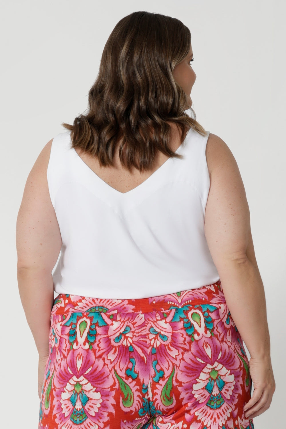 The sleeveless design makes this white cami an excellent choice for warmer weather, allowing you to stay cool and comfortable without sacrificing style. It’s tailored to offer a breezy and flattering fit, providing ease of movement while accentuating your shape with its v neck front and back feature and sleeveless silhouette.