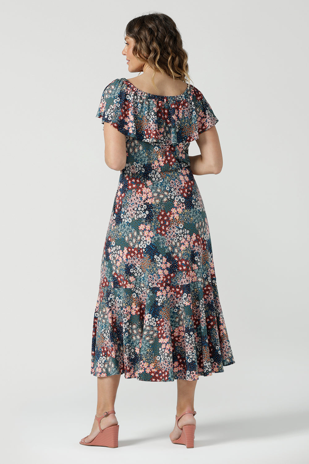 Back view of a woman wearing the Myla dress in Whimsy an off shoulder frill neck style. Side pockets and frill hem. Made in Australia and size inclusive for women size 8-24.