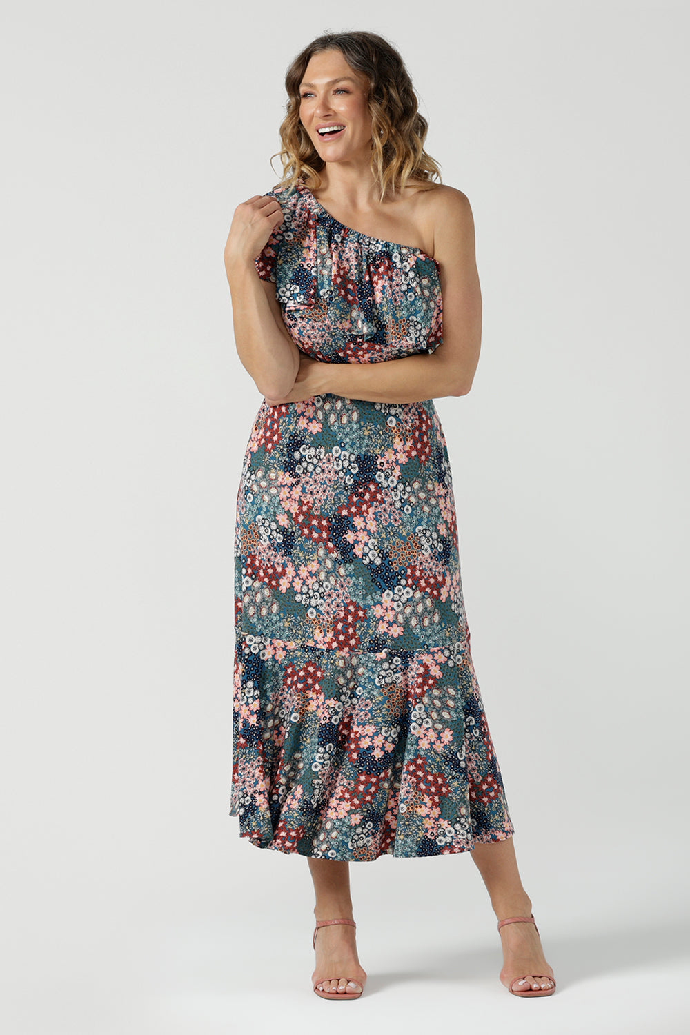 Worn on one shoulder. A woman wears the Myla dress in Whimsy an off shoulder frill neck style. Side pockets and frill hem. Made in Australia and size inclusive for women size 8-24.