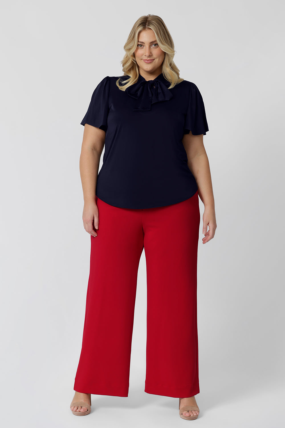 Showing good pants for plus size women, a size 18 woman wears high waisted wide leg trousers for curves in red stretch jersey.  Made in Australia for by Australian-made fashion brand, Leina & Fleur.  Stylish corporate wear for women. Made in Australia size 8 - 24. 