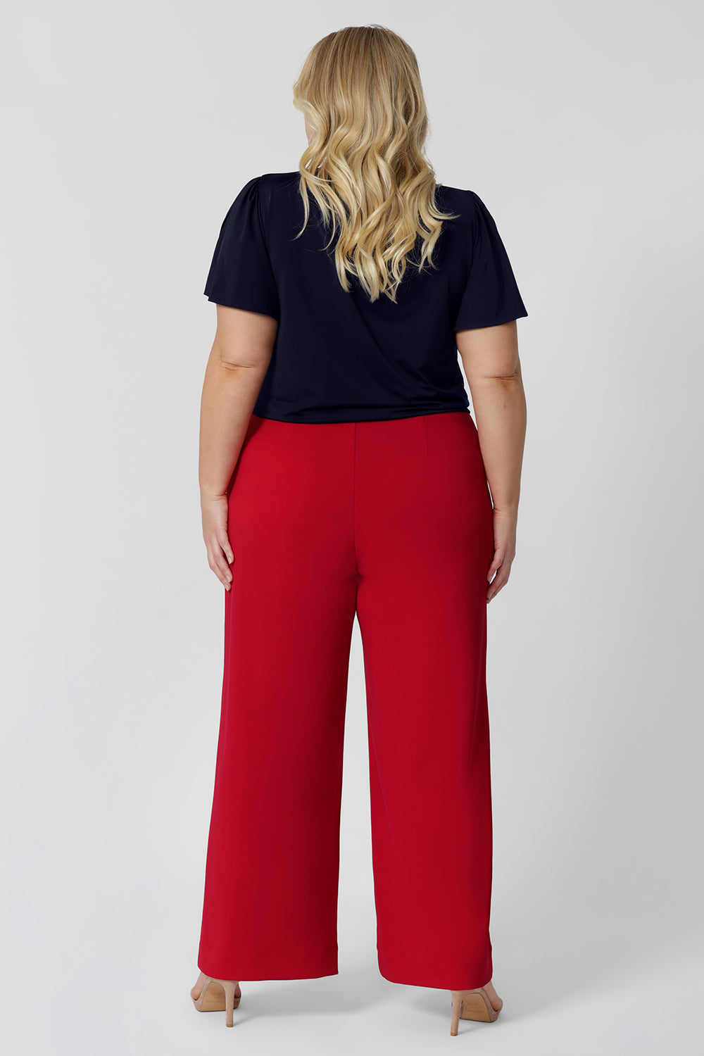 Back view of good pants for plus size women, a size 18 woman wears high waisted wide leg trousers for curvy women in red stretch jersey.  Made in Australia for by Australian-made fashion brand, Leina & Fleur.  Stylish corporate wear for women. Made in Australia size 8 - 24. 