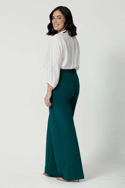 Side view of good workwear pants for petite women,  Green scuba crepe wide leg pants are worn with a white work shirt. These wide leg work trousers are made in Australia by Australia and New Zealand women's clothing brand, Leina & Fleur. Available to shop in sizes 8 to 24, this is workwear for plus size to petite height women. 