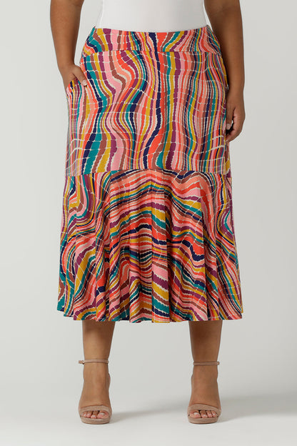 Close up of a size 12 woman wears Berit Maxi skirt in Kaleidoscope. A rainbow coloured print with The Kaleidoscope print features a vibrant swirl of colour in all colours of the rainbow, pink, red, yellow, turquoise, brown and cobalt on a white base. Made in Australia for women size 8-24.