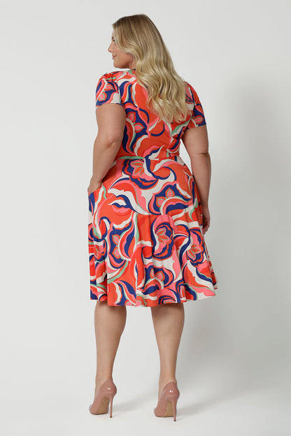 Back view of the best fixed wrap dress for plus size women. The Bibi Wrap Dress is new in Tangerine, Red, White, Mint Green and Purple retro print is shown on a curvy, size 18 woman. This plus size wrap dress is a fit and flare style with full, knee length skirt and pockets. With short sleeves it's a good summer dress. Made in Australia by Australian and New Zealand women's clothes brand Leina & Fleur.