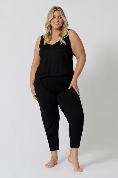 Showing a good lounge wear cami top for curve women, a size 18 woman wears a plus size cami top in black bamboo jersey. Thermo-regulating this sleeveless sleepwear top is a good top for menopause and night sweats. This black Cami top is Worn with tapered leg lounge pants. Shop lounge wear tops online in sizes 8-24.