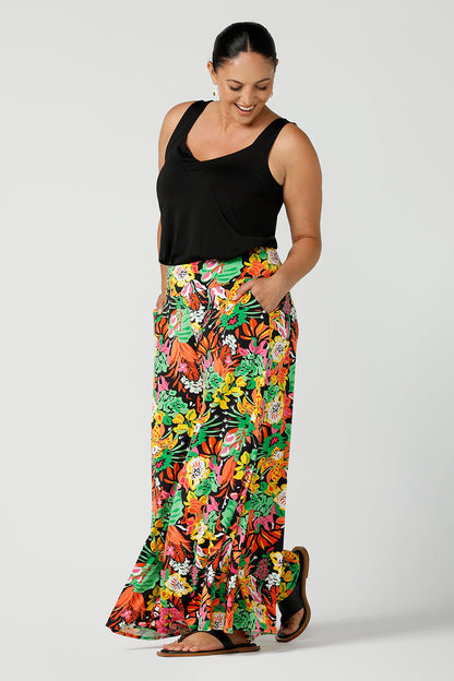 Side view of a size 12 woman wearing the Caspian Palazzo pant n a beautiful bright colourful print. In soft and lightweight jersey this pant features side pocket and a wide leg opening. Styled back with a black bamboo cami top and flat sandals. A perfect look for weekend wear. Made in Australia size 8-24.