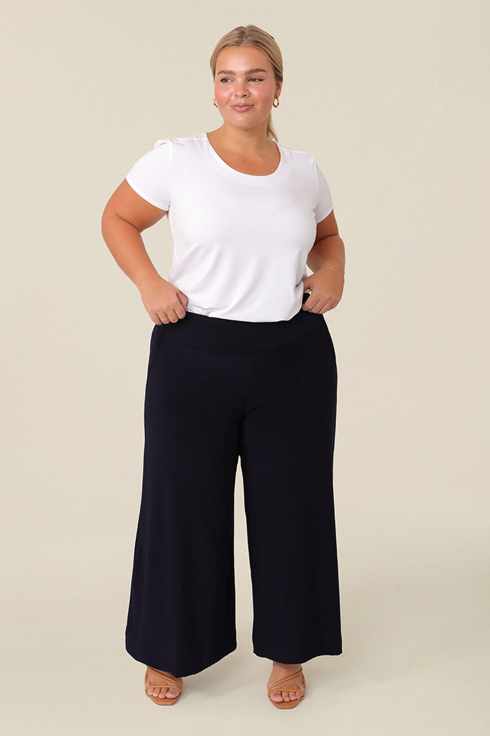 Good pants for petite women, a curvy, size 16 woman wears black culotte pants by Australian fashion brand, Leina & Fleur. Cropped trousers with a stretchy, pull on waistband, these easy-care wide leg pants are worn with a short sleeve top in white bamboo jersey.