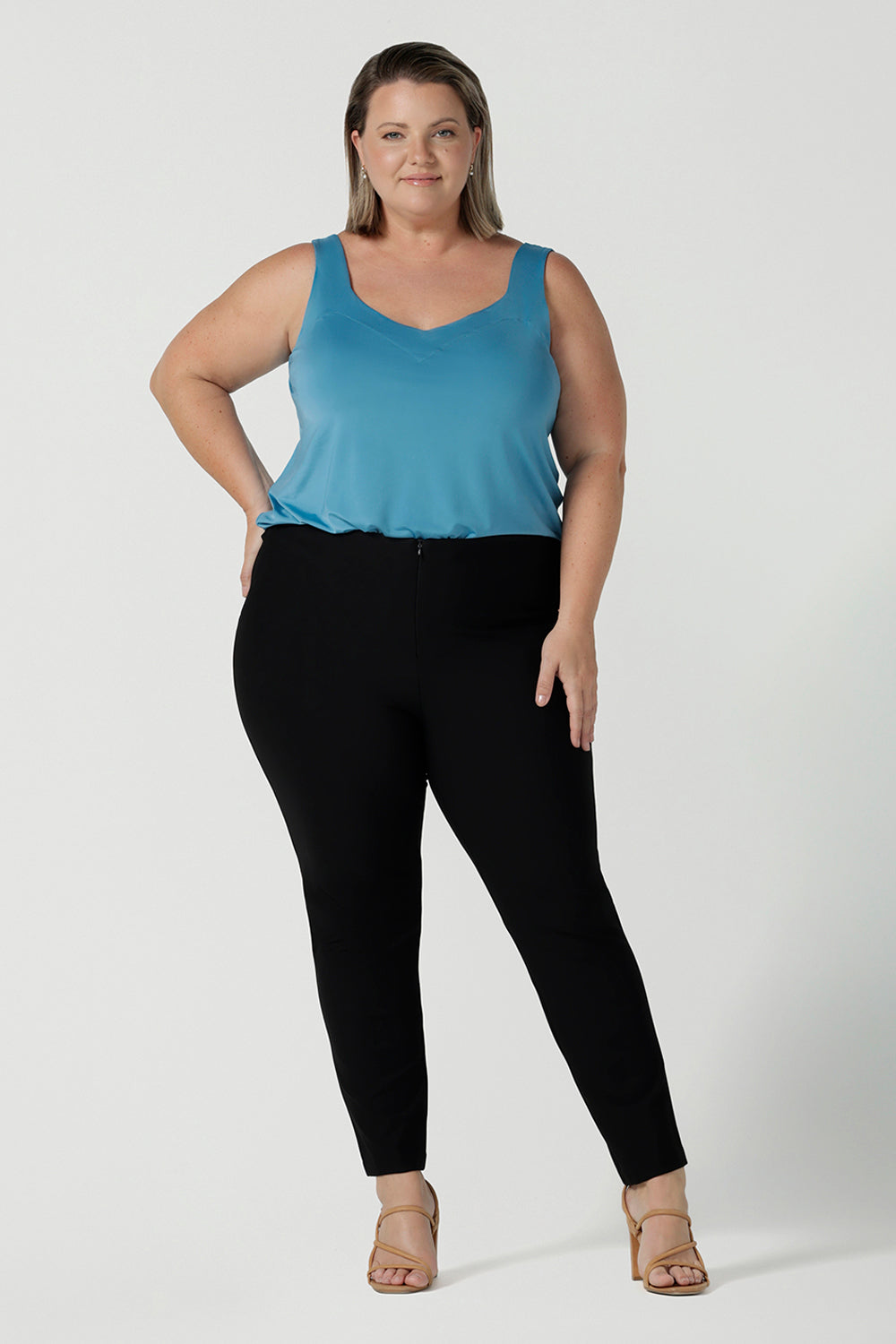 Size 18 Curvy woman wears the Brooklyn pant in black. It has a slim leg and functional pockets with invisible fly front detail. Styled back with an Eddy cami in Mineral.  Made in Australia for women size 8 - 24.