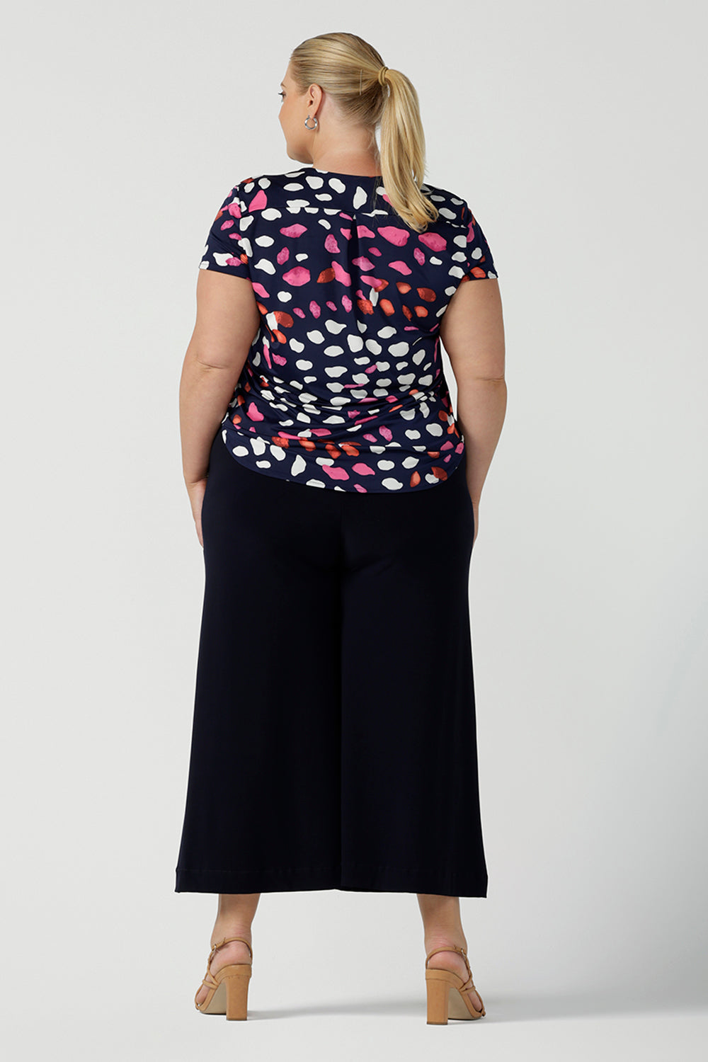 Back view of curvy size 18 woman wearing business casual wear for women.  Worn with an Emily top in Pink Mariposa animal print. The Dany Culotte is Australian made in a comfortable navy jersey fabric. Wide leg culottes for petite to plus size women 8-24.