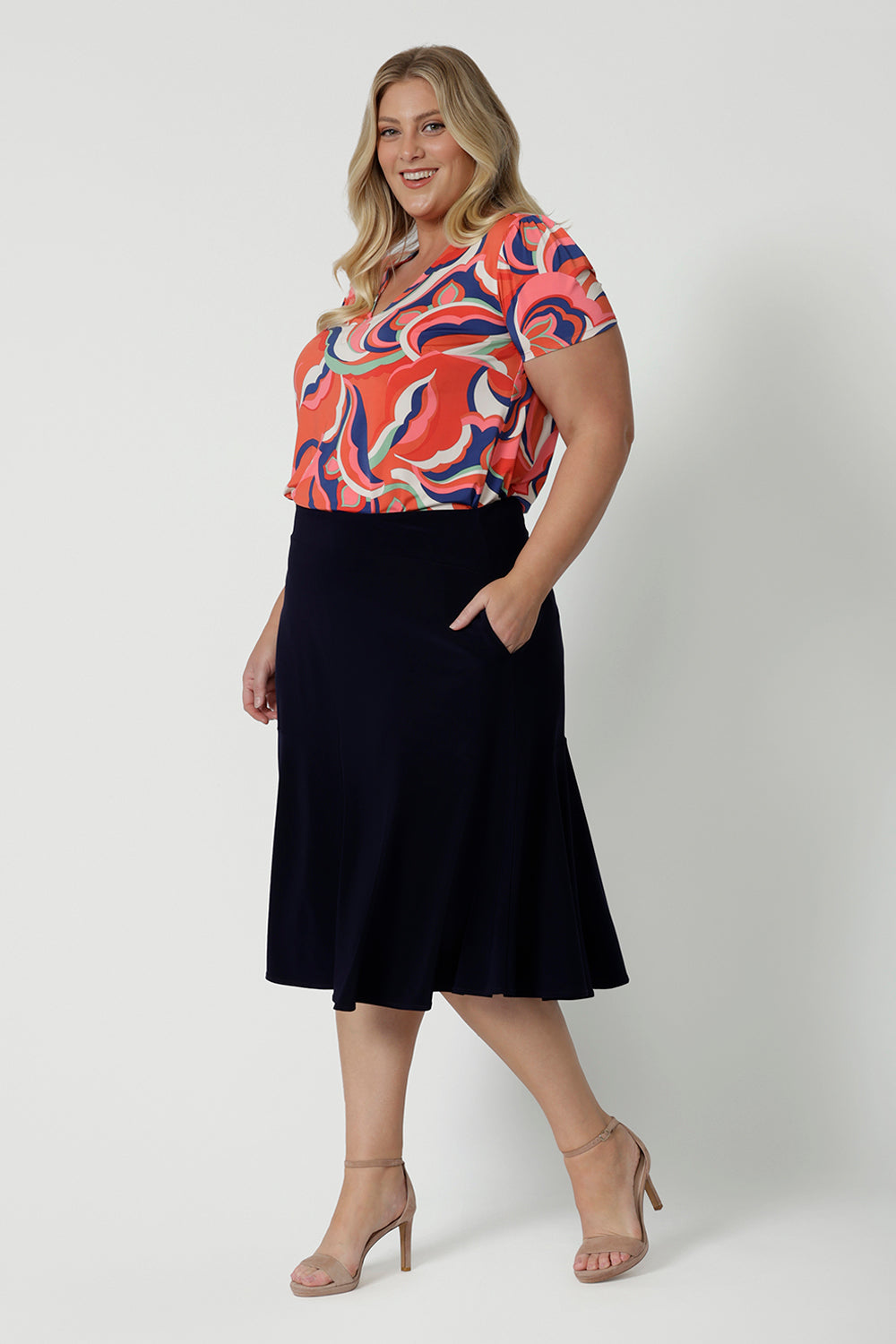 A good top for plus size women this tailored T-shirt top for summer, has a V-neck and short sleeves. Made in comfortable jersey, this printed top for women is worn by a size 18, curvy woman.  Worn with a knee length, navy skirt, this casual top  is good for travel and cruise wear. Made in Australia by Australian clothes label, Leina & Fleur in sizes 8 to 24.