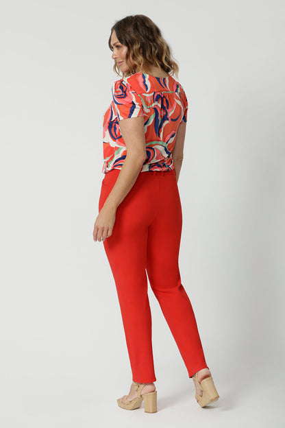 Made from tailored scuba crepe fabric in tangerine colour. Easy care pants are available in size 8-24. Australian made by clothing brand Leina & Fleur. Tapered leg pants are worn by size 18 model.
