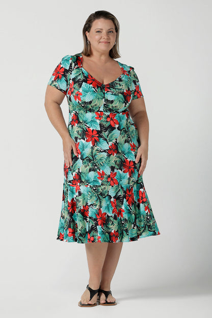 Size 18 Curvy woman wears the Jillian dress in Havana. A beautiful tropical print with a green leaf print and red flower on a white base that is tropical inspired. A sweetheart neckline style with an empire line. Tier on hem. Made in Australia for women. Size 8 - 24.