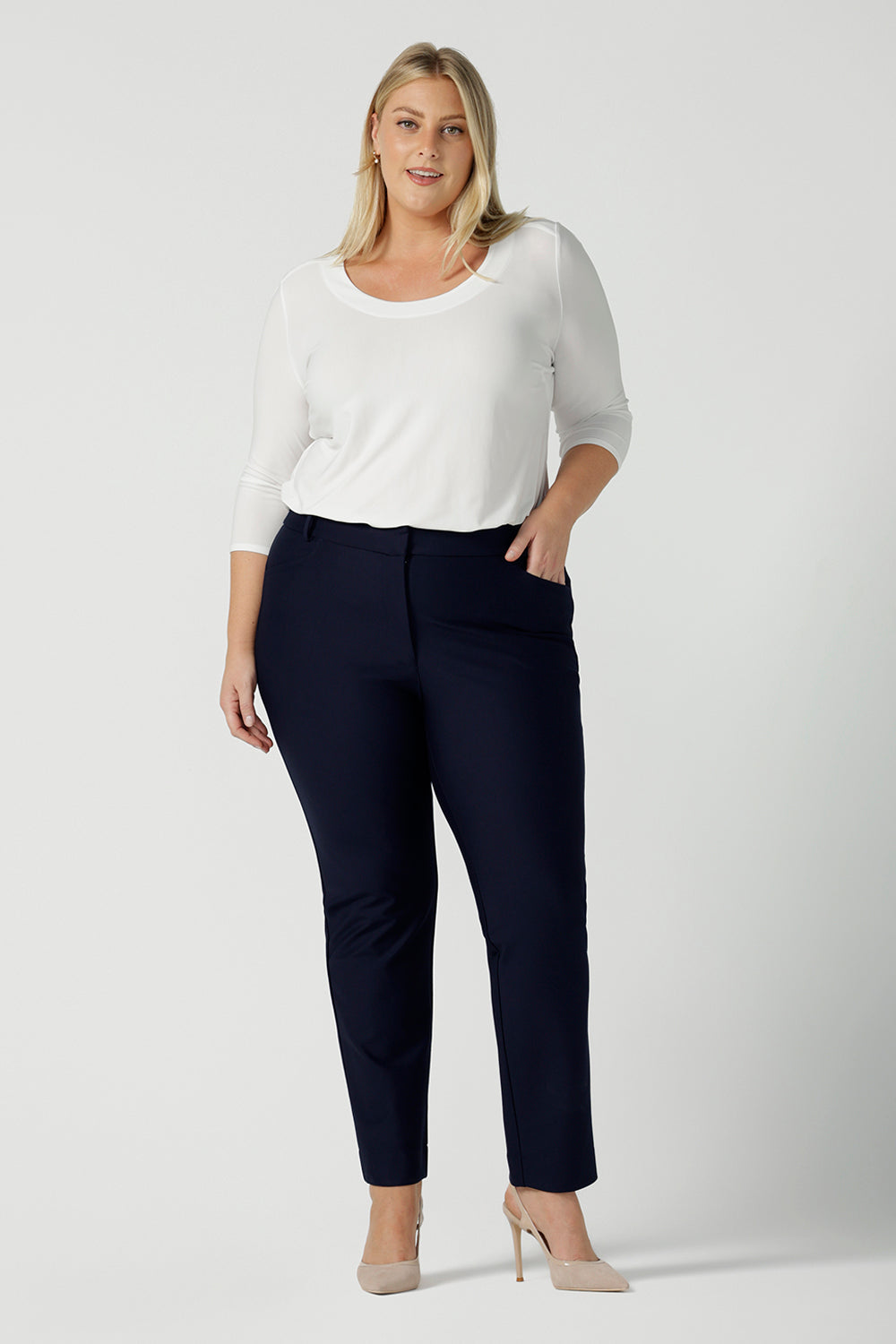 A size 18 woman wears the Lulu tailored pant in Navy. Made in Australia for women. A tailored pant in Navy with waistband and fly front with pockets. Styled back with the Jules. Size inclusive 8 - 24. 