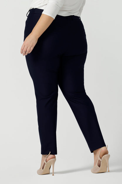 Back view of a size 18 woman wears the Lulu tailored pant in Navy. Made in Australia for women. A tailored pant in Navy with waistband and fly front with pockets. Styled back with the Jules. Size inclusive 8 - 24.