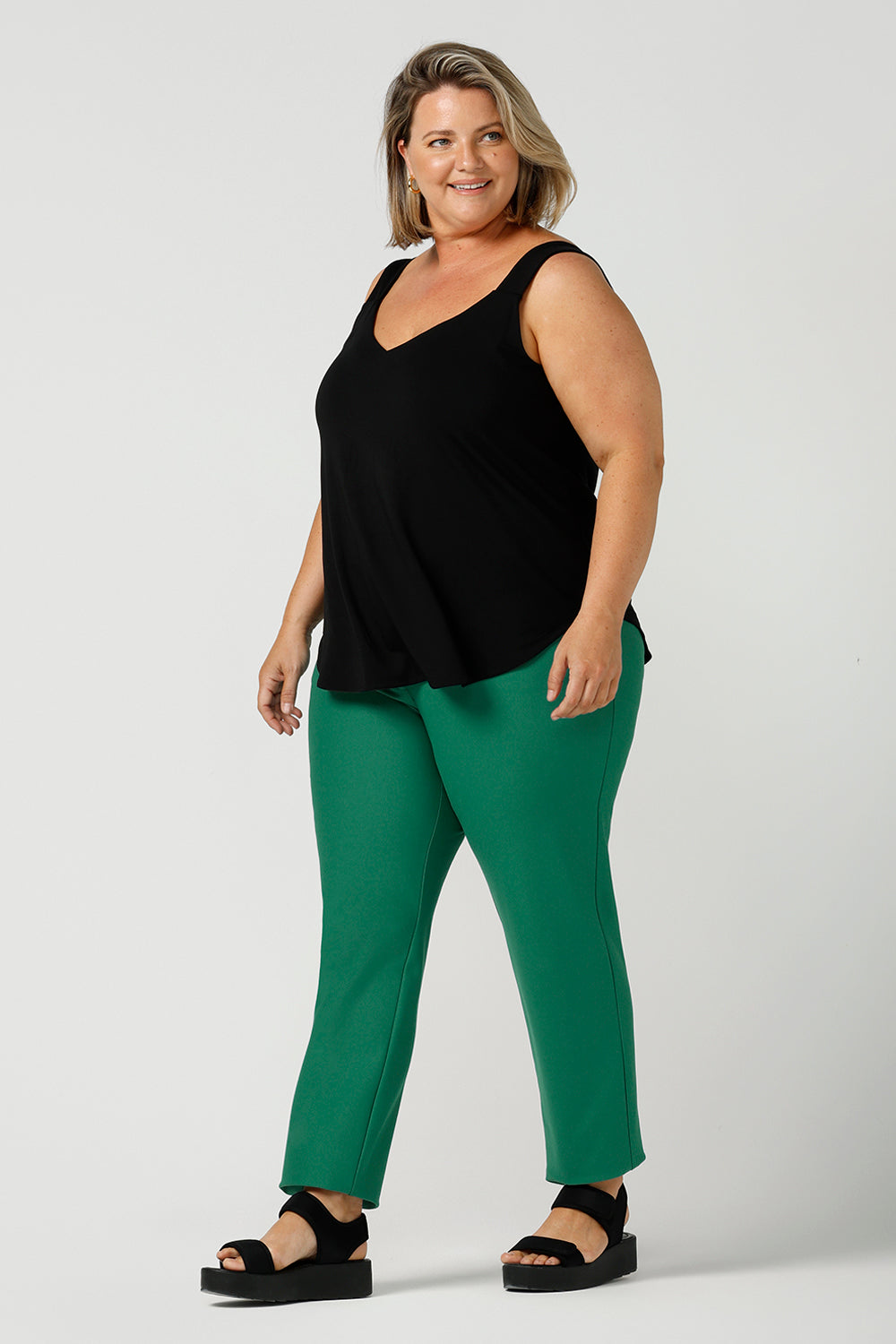 a size 18, fuller figure woman wears a bamboo cami with emerald green tailored pants. In black bamboo jersey, this top is a good addition to your capsule wardrobe for weekend wear, work and travel. Shop Australian-made dresses online is sizes 8 to 24.