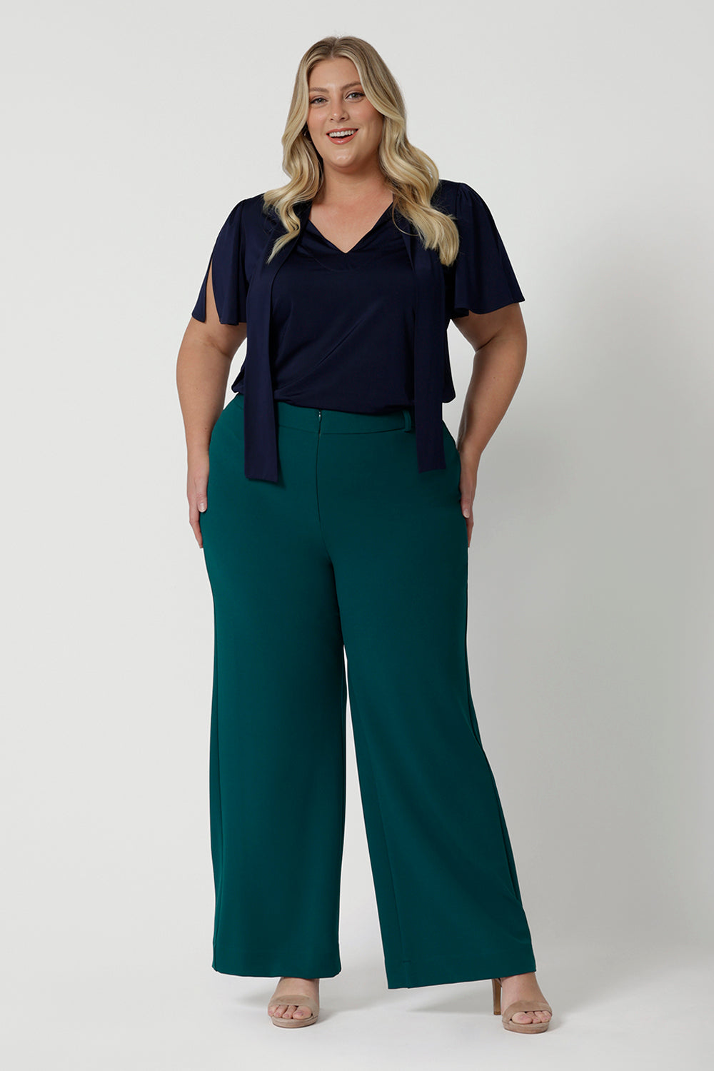 Showing good workwear for plus size women,  Green scuba crepe wide leg pants are worn with a navy jersey top. These wide leg work pants are made in Australia by Australia and New Zealand women's clothes brand, Leina & Fleur. Available to shop in sizes 8 to 24, this is workwear for plus size to petite height women. 