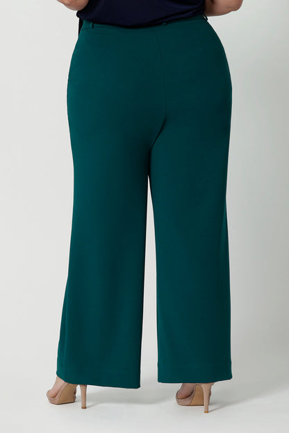 Back view of good workwear pants for plus size women,  Green scuba crepe wide leg pants are worn with a navy jersey top. These wide leg work pants are made in Australia by Australia and New Zealand women's fashion label Leina & Fleur. Available to shop in sizes 8 to 24, this is workwear for plus size to petite height women. 