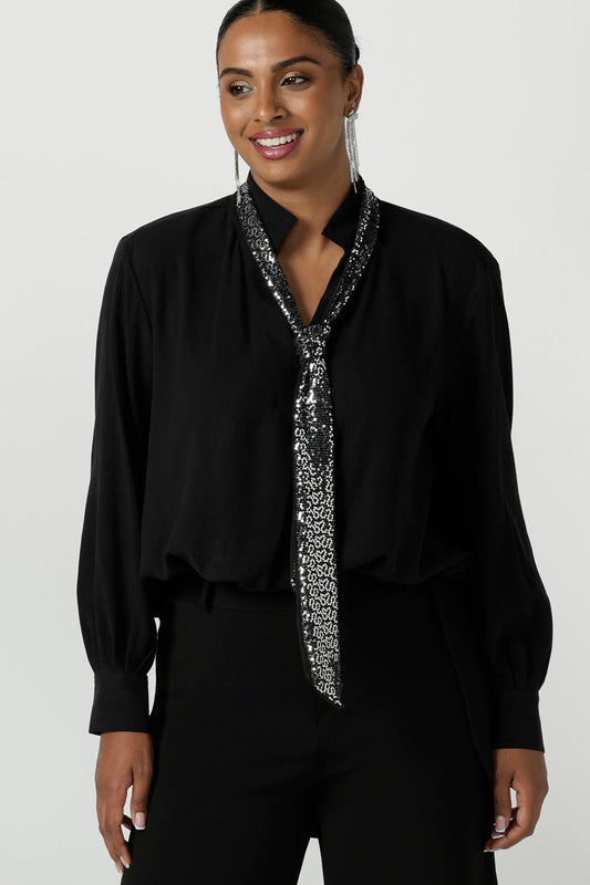 A size 10 woman wears the Silver Neck tie Silver Sequin Ellis and made in Australia size 8-24,  Styled back with a shirt in black and black scuba crepe pants. 