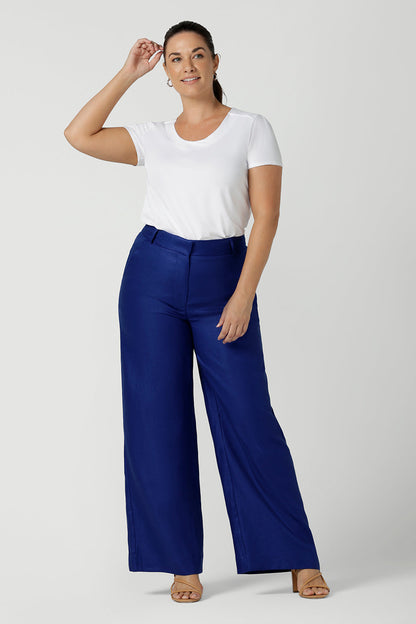 A size 12 woman wears the Ronnie Pant in Cobalt Linen. A high waist soft tailored pant with a fly front and belt loops. Styled back with a Sawyer top in white bamboo. Made in Australia for women size 8 - 24.