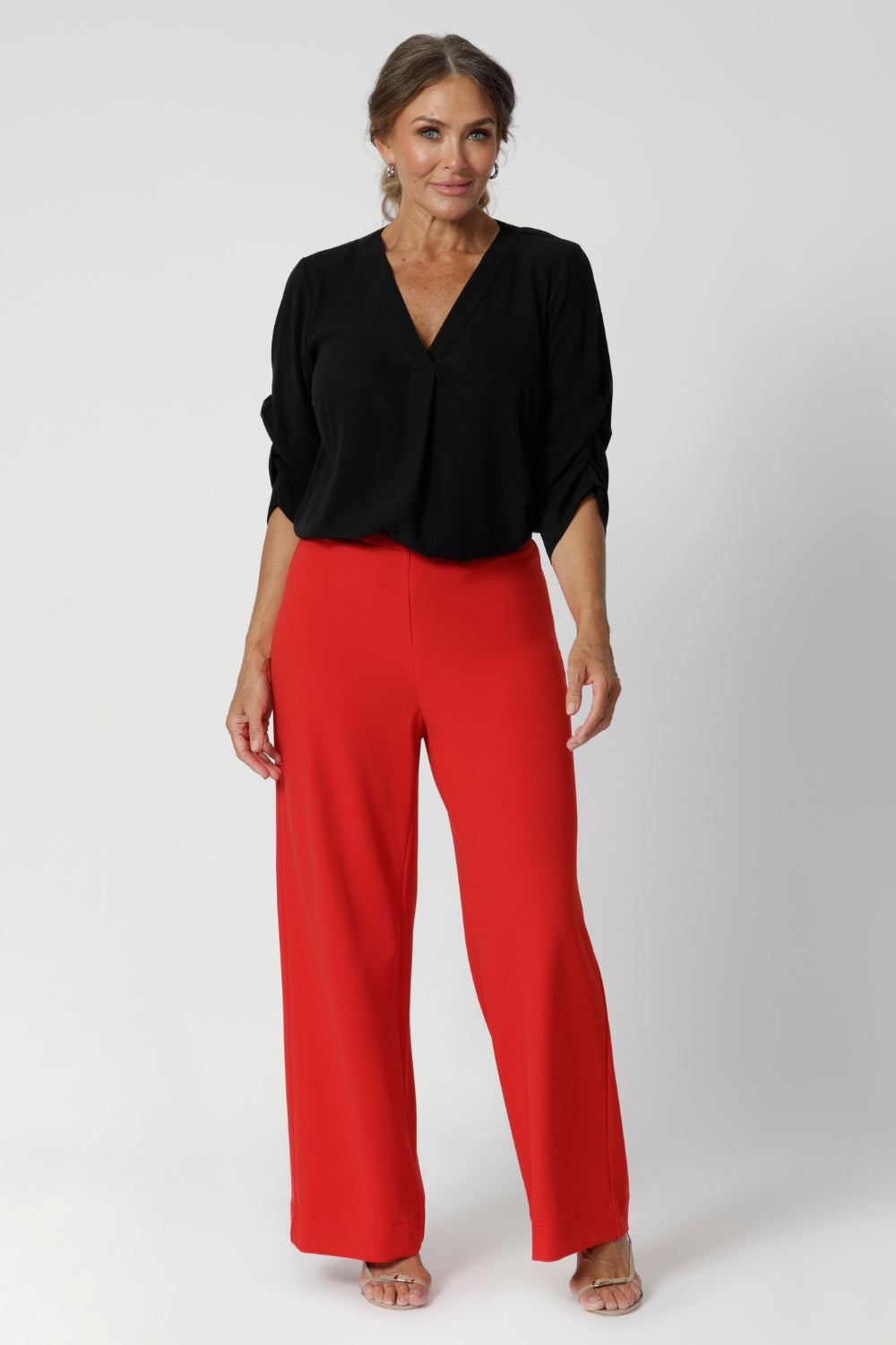 The shirt features a V-neckline, complemented by a tailored tuck at the center front, adding a structured yet feminine touch. The back neckline is finished with a facing and a neat tailored pleat for subtle detail.