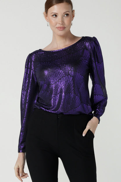 A size 10 woman wears the Zara top in purple metallic fabric. With balloon sleeves and a boat neckline. Styled back with black brooklyn ponte pants. The perfect cocktail suit set made in Australia for women size 8-24