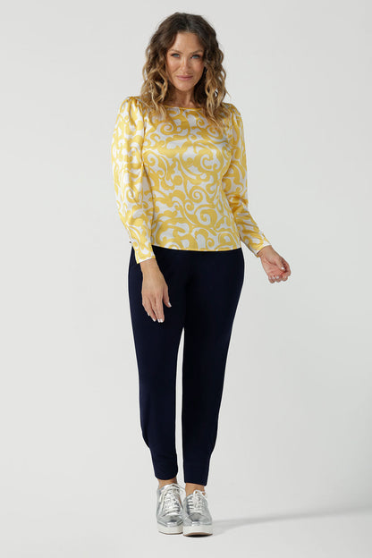 A size 10 woman wears a Zara Top in Yellow Swirl silk. A long sleeve blouse with fashion sleeve and made in 100% silk. Made in Australia for women size 8-24. Styled back with the Indi Tall Pant in Navy. 