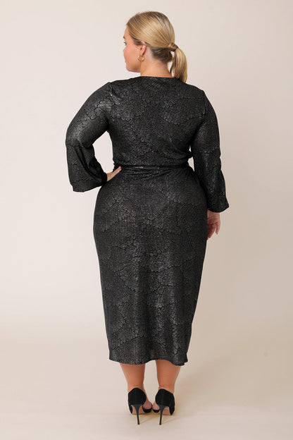 Back view of a curvy, petite height woman wearing a good cocktail dress for plus size women. A long sleeve wrap dress, this event dress shimmer in metallic foil print. A statement going out dress, the Carys dress is made in Australia by occasionwear brand Leina & Fleur.