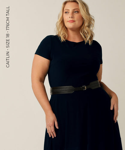 stretchy belt available in 9 sizes - plus sized model in corporate wear has black leather look belt on with silver buckle that fits around the waist 