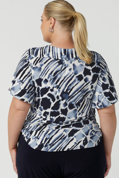 Back view of a  plus size, size 18 woman wearing a blue and white print jersey, V-neck top with flutter sleeves. A good top for summer casual wear or as a workwear top this quality women's top is made in Australia. Shop made in Australia tops in petite to plus sizes online at Australian women's clothing label, Leina & Fleur.