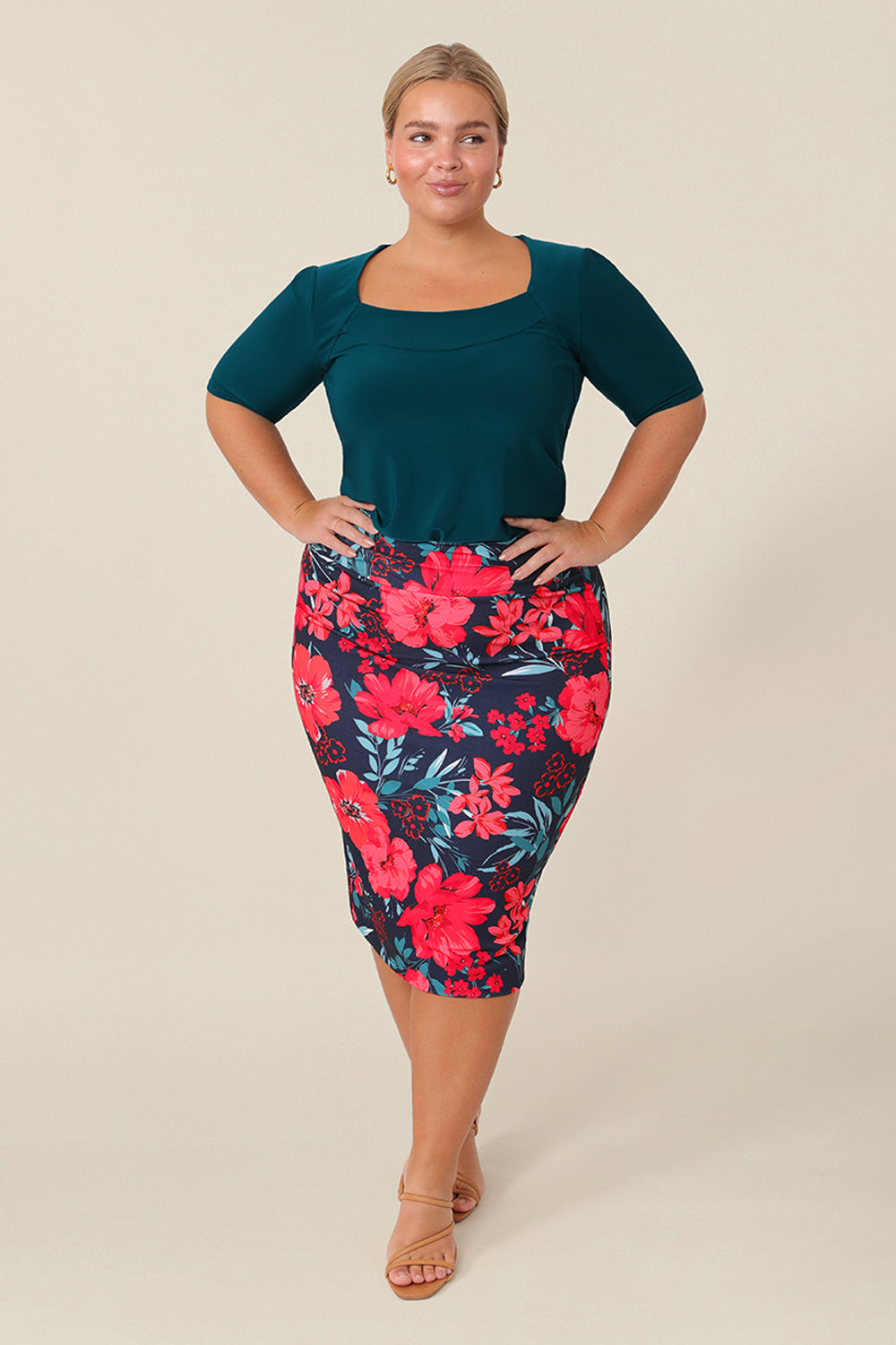 A curvy size 16 woman wears good work wear for plus size women, a knee-length tube skirt in floral print. Made in Australia, shop this work skirt online in sizes 8 to 24.