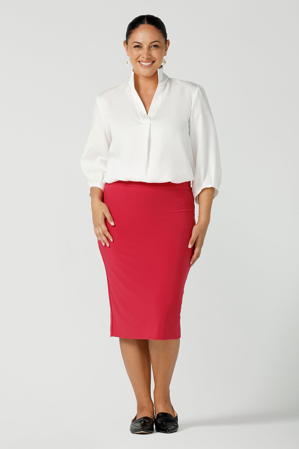 A curvy size 12 Woman wears a fuchsia Andi tube skirt. Styled back with the Arley shirt in white. A bright pop of colour for your workwear wardrobe. Designed and made in Australia for women size 8 - 24. 