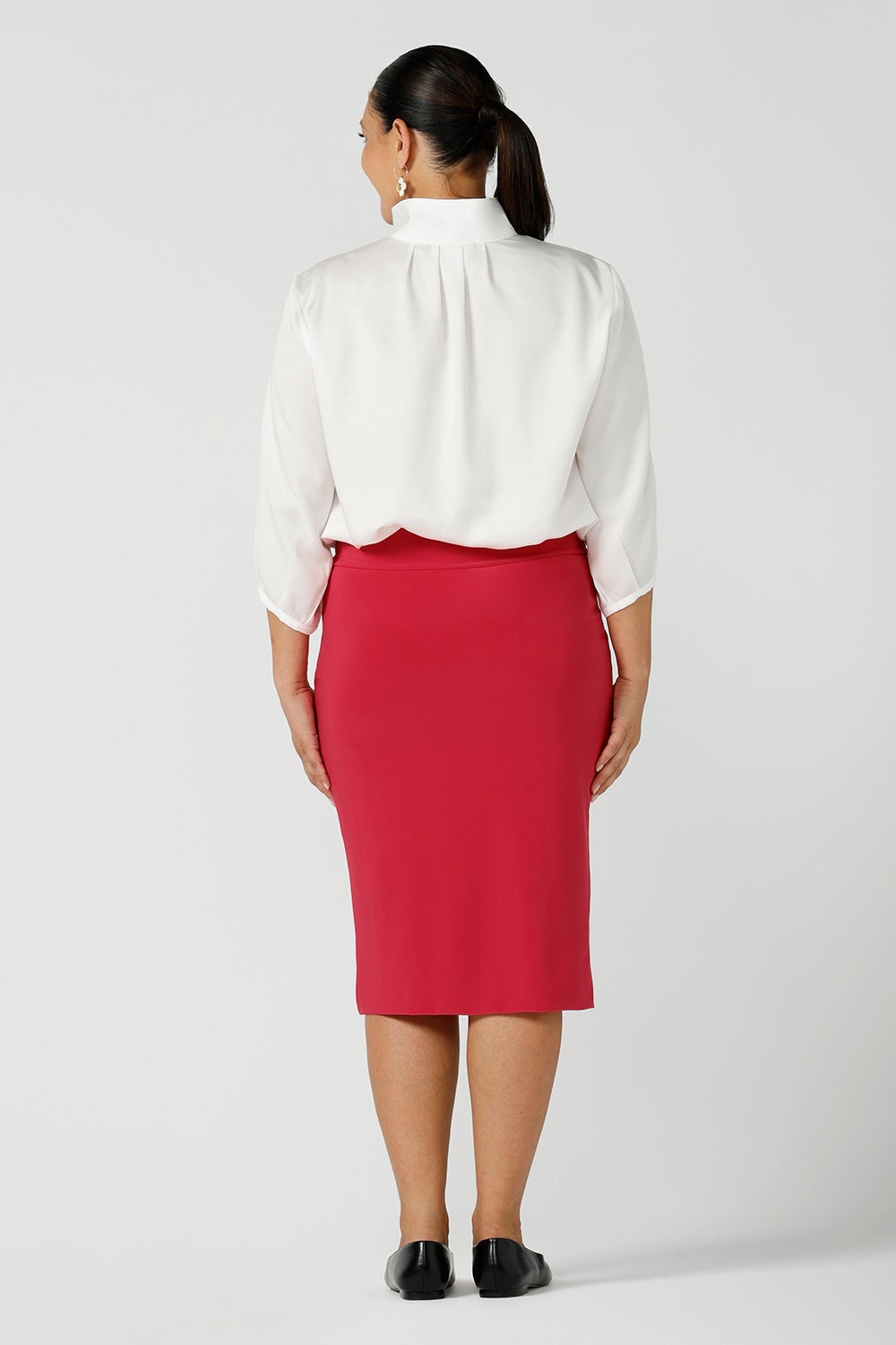 Bcak view of a curvy size 12 Woman wears a fuchsia Andi tube skirt. Styled back with the Arley shirt in white. A bright pop of colour for your workwear wardrobe. Designed and made in Australia for women size 8 - 24.