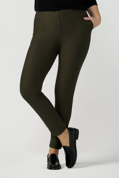 A size 10, 40 plus woman wears slim leg, cropped length pants in olive green.  Tailored skinny pants with pockets and a front zip fastening these made-in-Australia  work pants fit petite, mid size and plus size women.