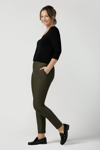 A size 10, 40 plus woman wears slim leg, cropped length pants in olive green with a 3/4 sleeve black top.  Tailored skinny pants with pockets and a front zip fastening these made-in-Australia  work pants fit petite, mid size and plus size women.