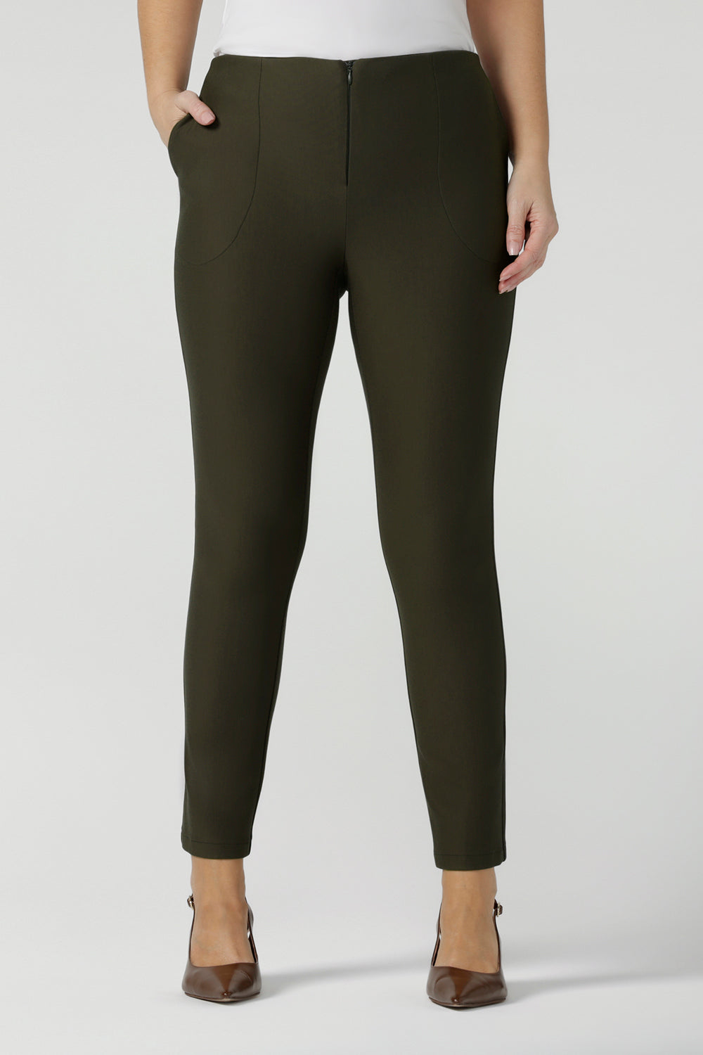 Close up of slim leg, cropped length pants in olive green. Tailored skinny pants with pockets and a front zip fastening these made-in-Australia  work pants fit petite, mid size and plus size women.