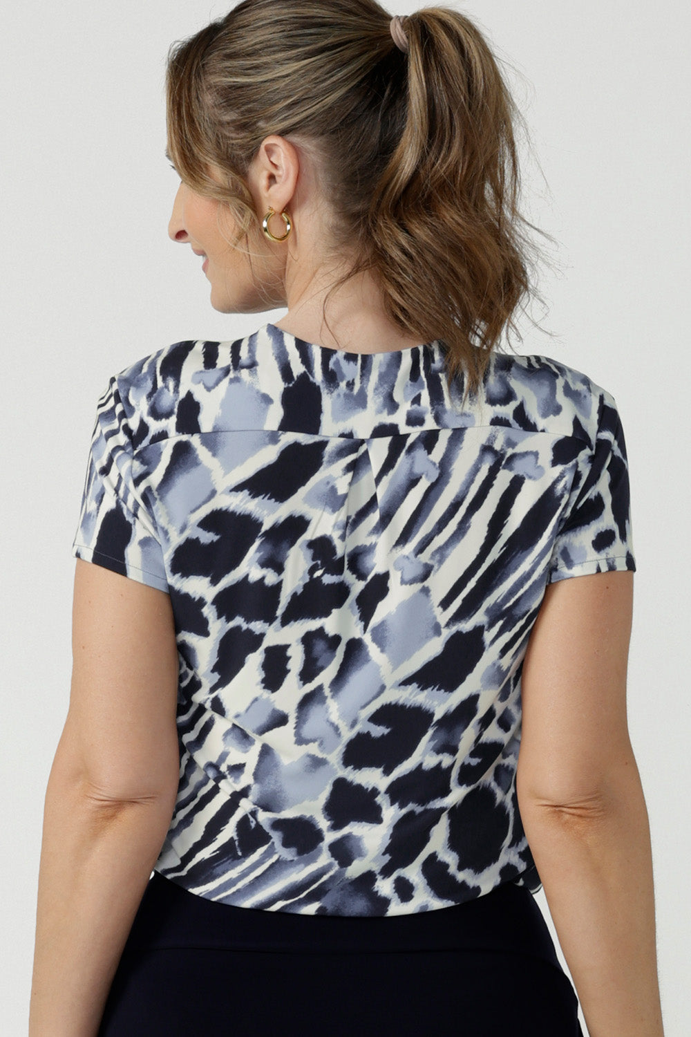 Back view of a good top for curvy women, this short sleeve V-neck top is tailored to fit women's curves. Shown on a size 10, 40 plus woman, this blue and white print jersey top is Australian-made. Wear this top for work and casual wear. Shop online in inclusive sizes 8 to 24 at Australian women's fashion online store,, Leina & Fleur.