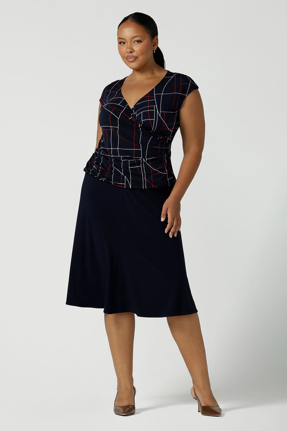 A size 16 curvy woman wearing the Cassidy skirt in Navy. A comfortable work wear wear corporate casual skirt. Style back with a Finley top in Abstract. Made in Australia for women size 8 - 24.