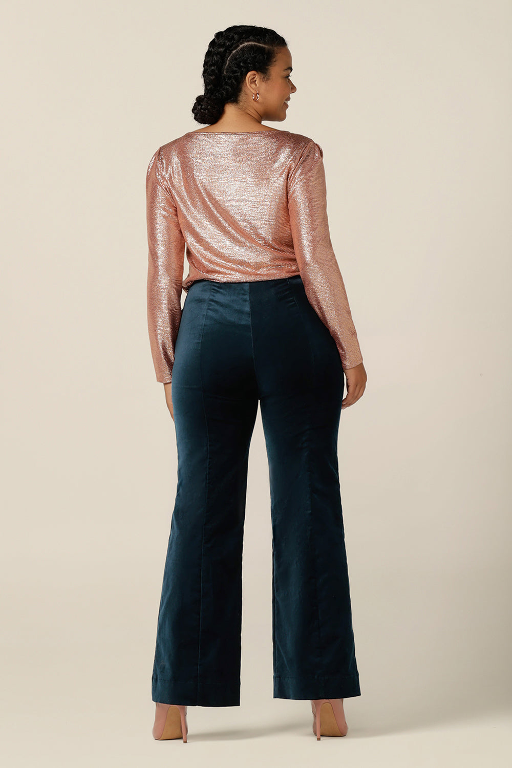 Back view of a size 12 woman wearing a shimmering pink sparkly top with high scoop neck and long sleeves, with flared leg velveteen trousers. Simple and easy-to-wear, this comfortable evening top is made in Australia in sizes 8 to 24. 