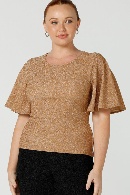 A size 12, fuller figure woman wears a sparkly honey glam top with flutter. Sleeves. Made in Australia by Australian and New Zealand women's clothing company, this shimmer jersey top wears well with evening and occasion-wear skirts, pants and suit jackets.