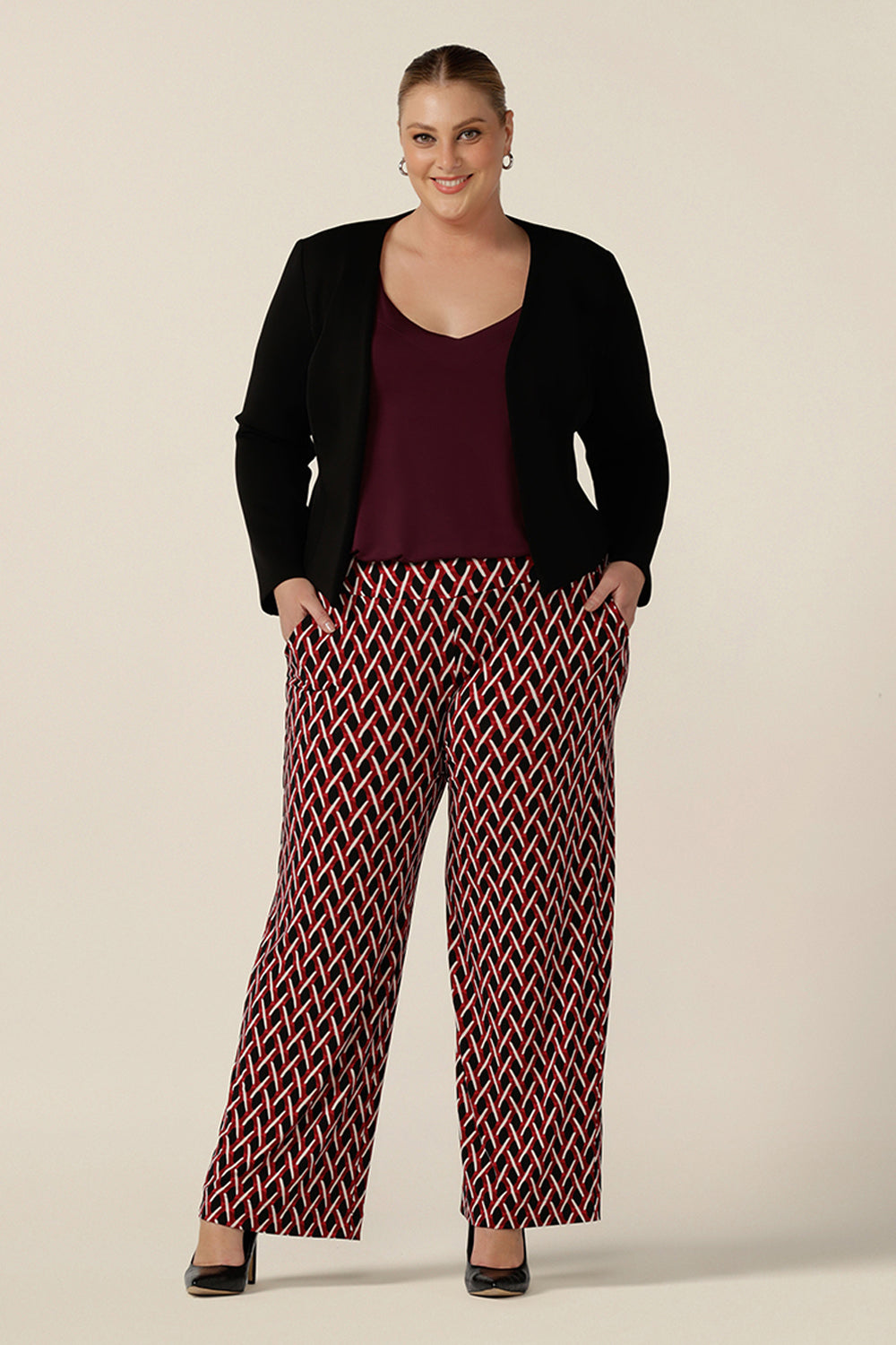 Good pants for plus size women, these geometric print pants are straight cut , wide leg trousers with a wide, pull-on waistband. Styled for work wear, these office pants are worn with a plum cami top and workwear jacket in black. Made in Australia, shop online now in sizes 8 to 24.