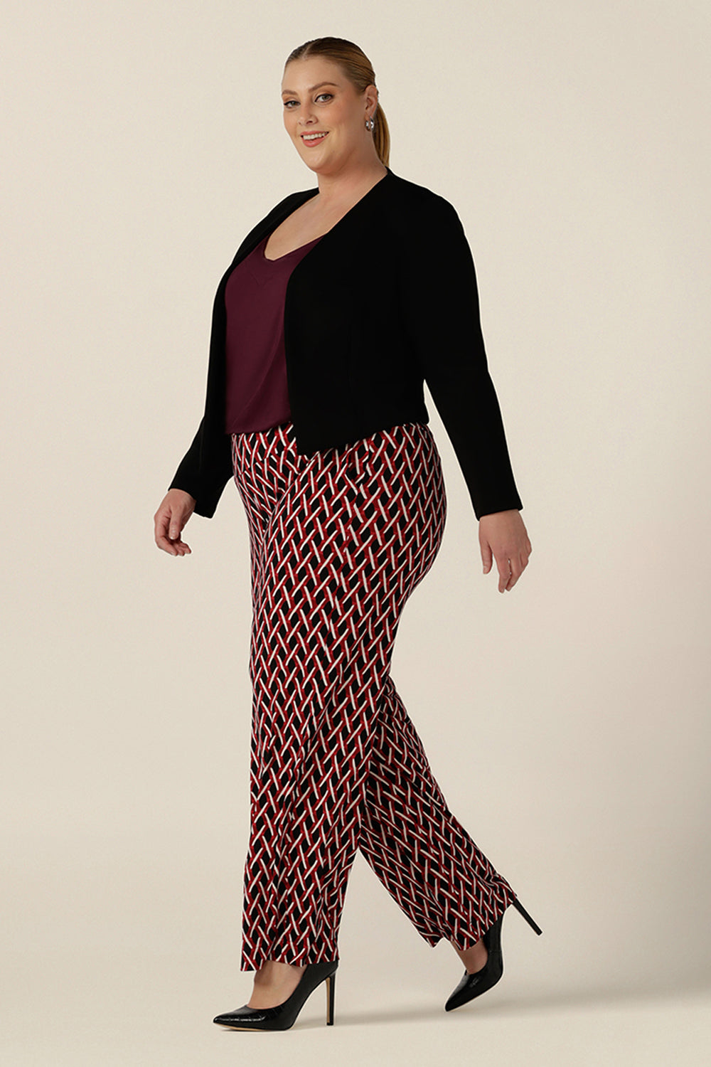 Side view of workwear pants for plus size women, these geometric print pants are straight cut , wide leg trousers with a wide, pull-on waistband. Styled for work wear, these office pants are worn with a plum cami top and workwear jacket in black. Made in Australia, shop online now in sizes 8 to 24.