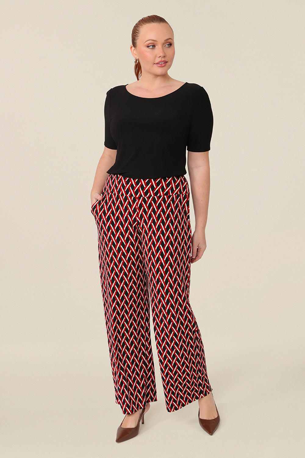 Good pants for curvy women, these geometric print pants are straight cut, wide leg trousers with a wide, pull-on waistband. Styled for work wear, these office pants are worn with a scoop neck, black short sleeve top. Made in Australia, shop online now in sizes 8 to 24.