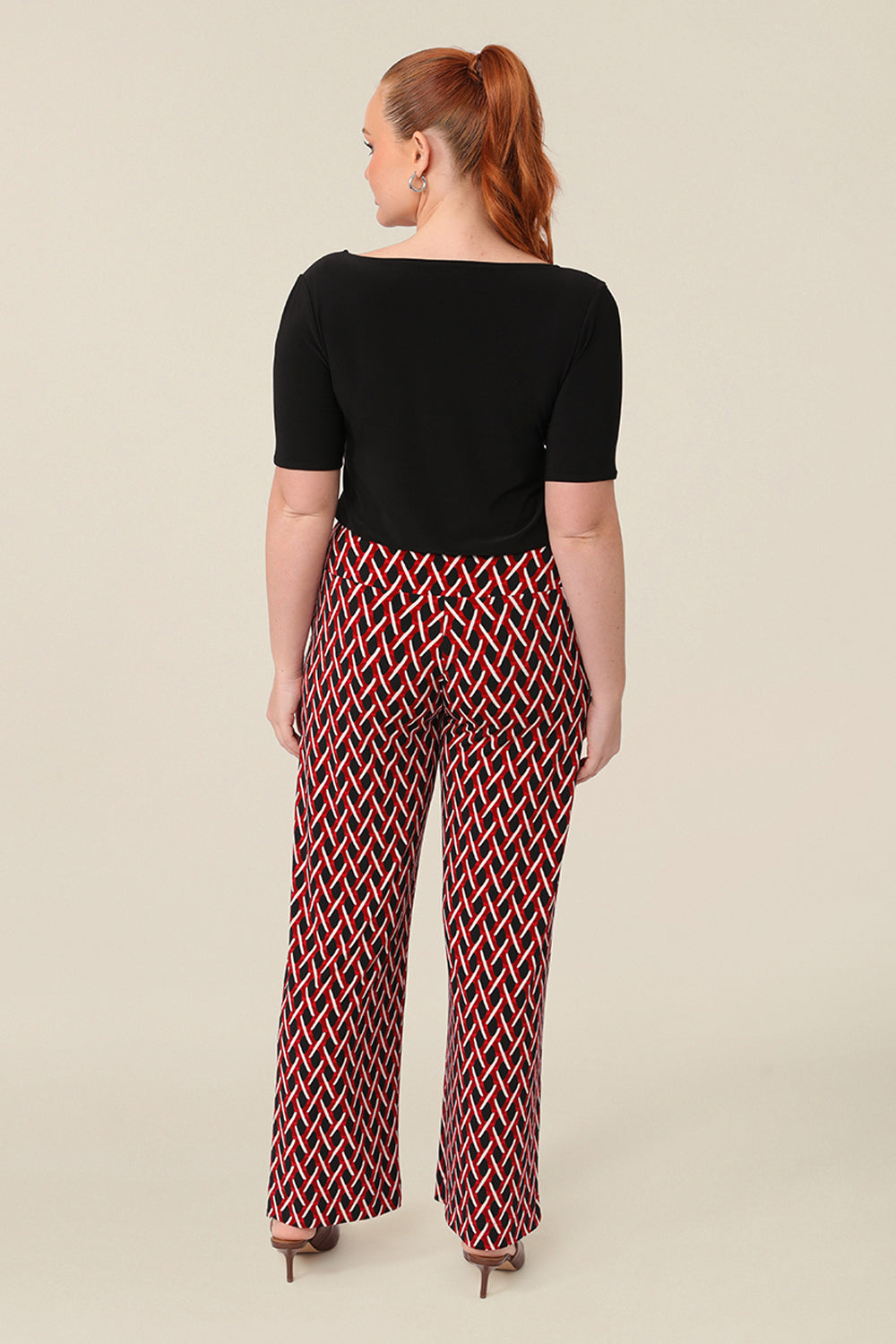 Back view of good work pants for curvy women. These geometric print trousers are straight cut, wide leg pants with a wide, pull-on waistband. Styled for work wear, these office pants are worn with a black short sleeve top. Made in Australia, shop online now in sizes 8 to 24.